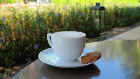 A cup of coffee and a cookie on a saucer on a table Stock Footage 264159510