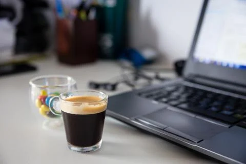 Cup of coffee and cup of colored chocolate filled sweets next to Stock Photos