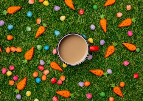 Cup of coffee and Easter chocolate eggs with cookie carrots on green grass Stock Photos