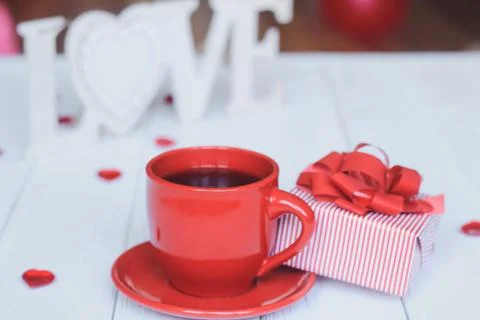 Cup of coffee and gift on blurred background. Stock Photos
