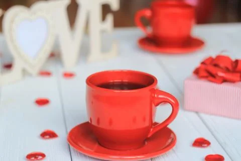Cup of coffee and gift on blurred background. Stock Photos