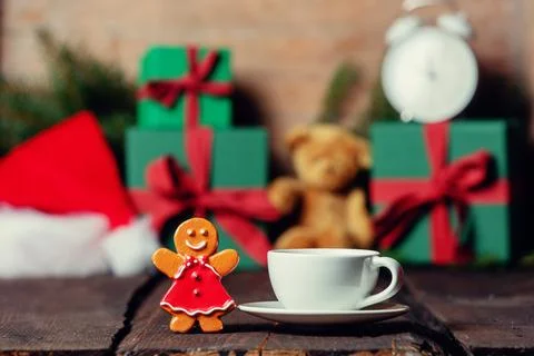 Cup of coffee and giingerbread cookie toy on wooden table with gifts Stock Photos