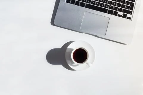 Cup of coffee and laptop computer on white table, top view.  Stock Photos