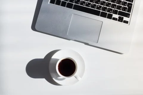 Cup of coffee and laptop computer on white table, top view Stock Photos