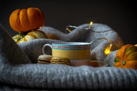 A cup of coffee and macaroons on the background of pumpkins and garland light Stock-Fotos