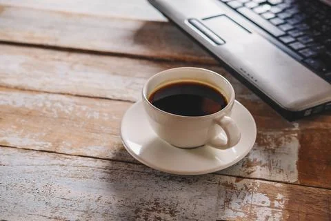 .A cup of coffee and a notebook computer on the desk Stock Photos