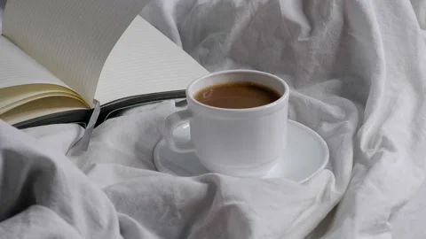 A cup of coffee and a notebook on a white bed. Stock Footage 158103796