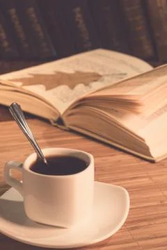 A cup of coffee and an open book on the table Stock Photos