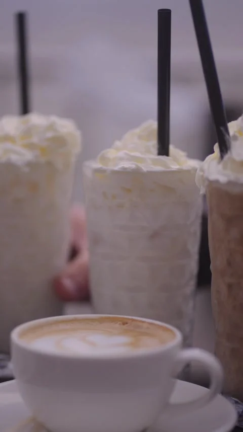 A cup of coffee and two milkshakes in the background. Stock Footage 255209897