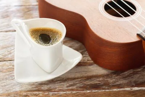 Cup of coffee and ukulele on rustic wood. Stock Photos