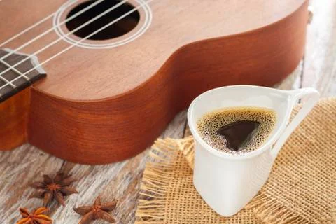 Cup of coffee and ukulele on rustic wood. Stock Photos
