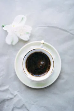 Cup of coffee and white flower on gray background. top view Foto stock