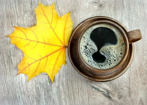Cup of coffee and yellow maple leaves on a wooden table Stock Photos