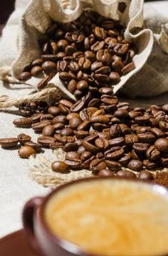 A cup of coffee on a background of coffee and ground beans on burlap. Stock Photos