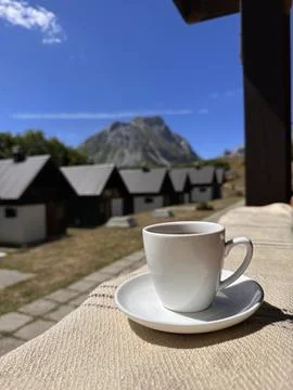A cup of coffee on the background of mountain and the cottage village Stock Photos