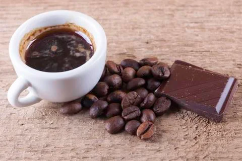 Cup, coffee beans, chocolate, wooden board closeup top view background Stock Photos