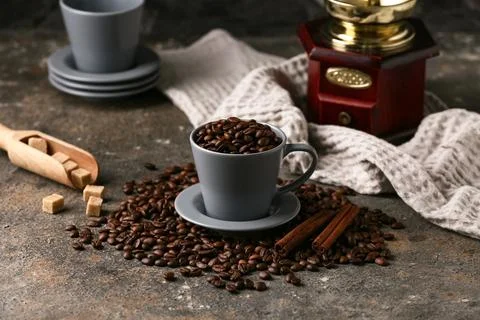 Cup with coffee beans, sugar cubes and grinder on grey grunge background Stock Photos