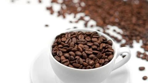 A Cup with coffee beans on a white background. Lots of coffee beans. Stock Photos
