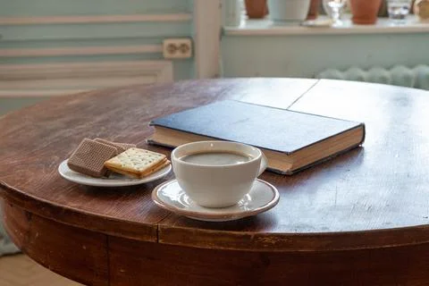 Cup of coffee with biscuits and a book on a wooden table. Coffee break and .. Fotos Stock