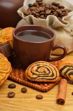 Cup of coffee with biscuits, coffee beans in bags and cinnamon sticks Stock Photos