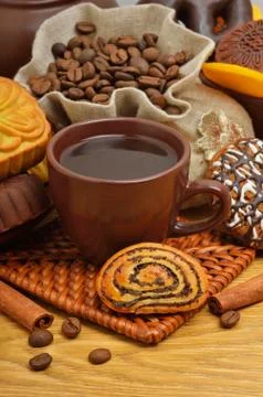 Cup of coffee with biscuits, coffee beans in bags and cinnamon sticks Stock Photos
