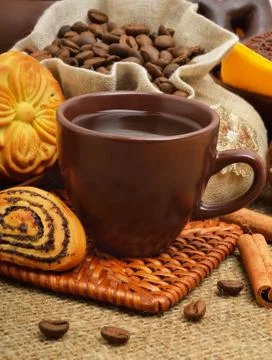 Cup of coffee with biscuits, coffee beans in bags and cinnamon sticks Stock Photos