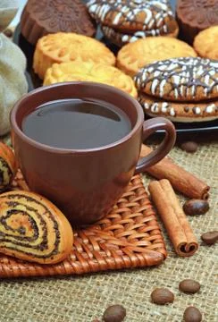 Cup of coffee with biscuits, coffee beans in bags and cinnamon sticks Stock Photos