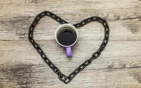 Cup of coffee in black rusty chain. Stock Photos