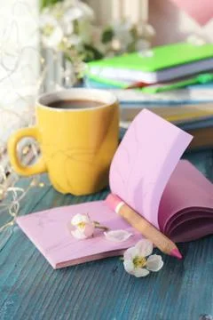 Cup of coffee, blank notebook for notes, a stack of books, apple flowers Stock Photos
