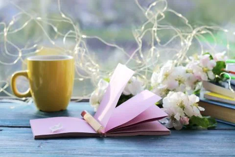 Cup of coffee, blank notebook for notes, a stack of books, apple flowers Stock Photos