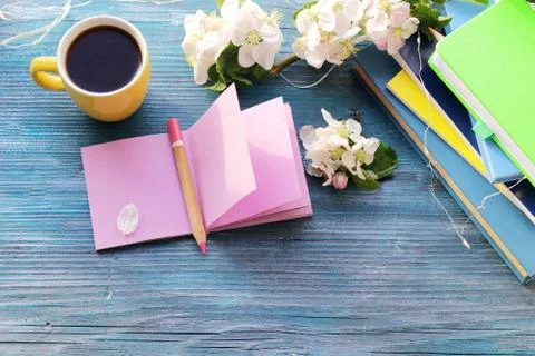 Cup of coffee, blank notebook for notes, a stack of books, apple flowers Stock Photos