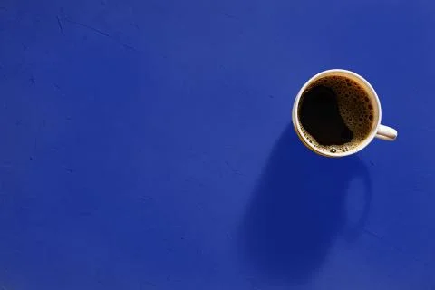 Cup of coffee on blue background, top view Stock Photos