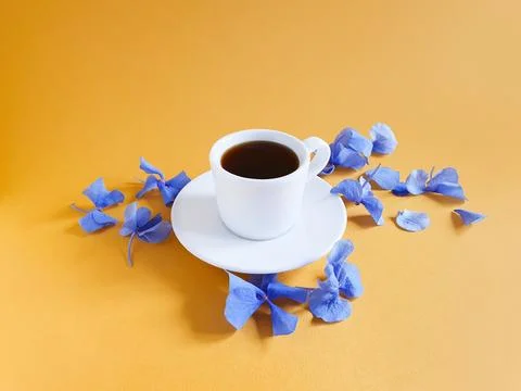 Cup of coffee, blue hydrangea flowers on yellow orange background Stock Photos