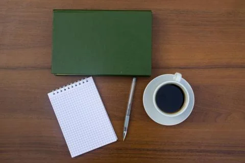 Cup of coffee, book, notepad and pen on wooden desk Stock Photos