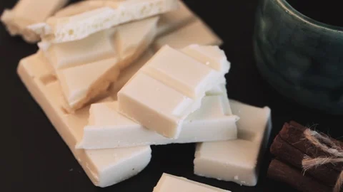 Cup of coffee, broken white and black chocolate bars and stack of cinnamon on Video stock 89401690