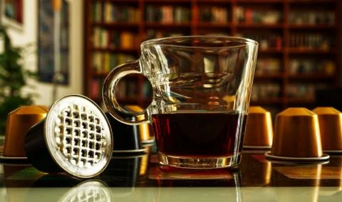 Cup of coffee with capsules on the background Stock Photos