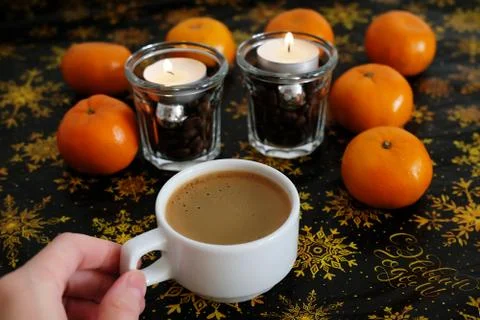 Cup of coffee on christmas pattern background. Tangerines and coffee candles in Stock Photos