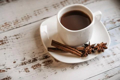 A Cup of coffee with cinnamon sticks on a light wooden background. Stock Photos