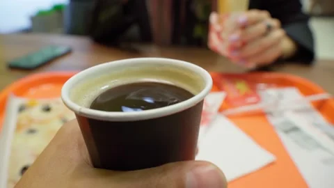 Cup of coffee close-up. A man holds a paper cup in a fast food restaurant Stock Footage 163704764