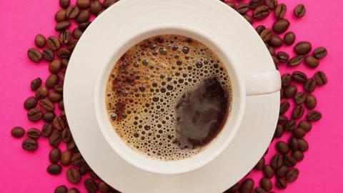 A cup of coffee with coffee beans on a bright pink background. Stock Footage 261990808