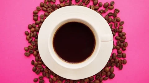 A cup of coffee with coffee beans on a bright pink background. Close-up. Stock Footage 261990812