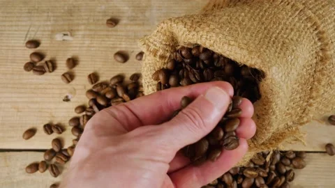 A cup of coffee. Coffee beans in hand. A sack of coffee on a wooden background, Video stock 160570875