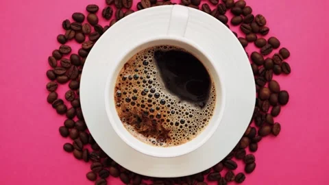 A cup of coffee with coffee beans rotates on a bright pink background. Stock Footage 286194575