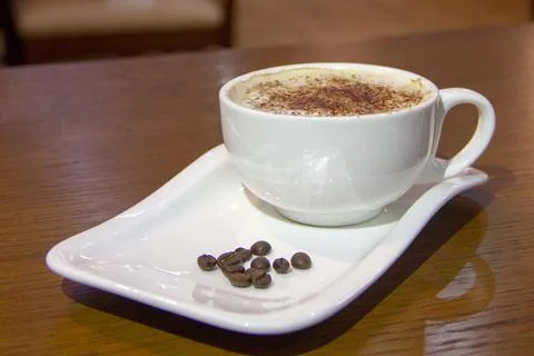 A cup of coffee with coffee beans on the side Stock Photos