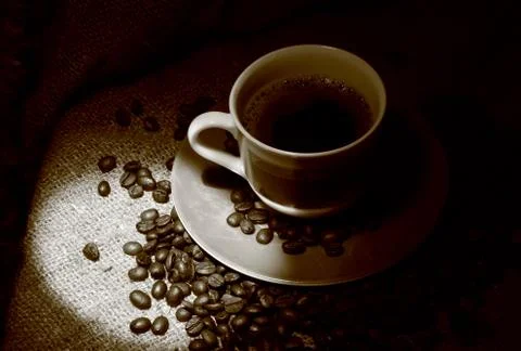 Cup of coffee with coffee beans standing on a sacking Stock Photos