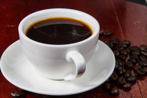 Cup of coffee with coffee beans on a table Foto stock