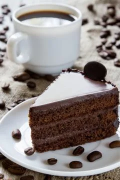 Cup of coffee, coffee beans on table with sackcloth, piece of chocolate cake Stock Photos