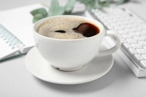 Cup of coffee with computer keyboard on grey background Stock Photos