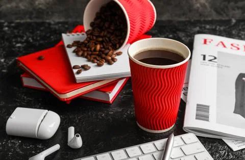 Cup of coffee with computer keyboard, magazine and earphones on black grunge  Stock Photos