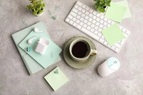Cup of coffee with computer keyboard, mouse and earphones on grey grunge back Stock Photos